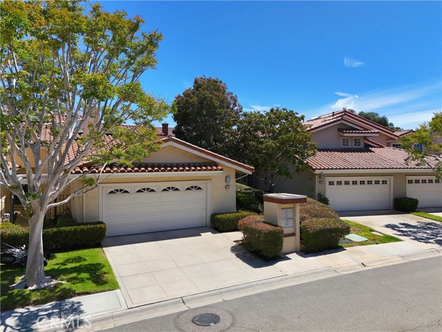 Suburban street scene with two attached homes, each having a white two-car garage and tiled roofs on a sunny day.